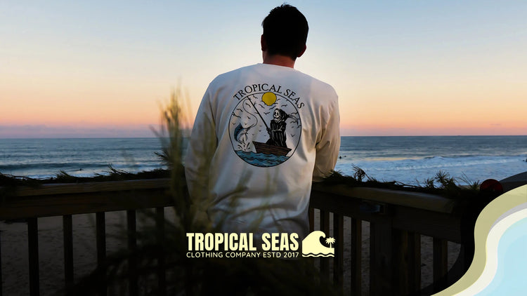 Sustainable Fall Favorites collection at Tropical Seas Clothing, featuring beach-ready, eco-conscious styles for ocean lovers. Person wearing fall-inspired tropical apparel overlooking a scenic coastline at sunset.